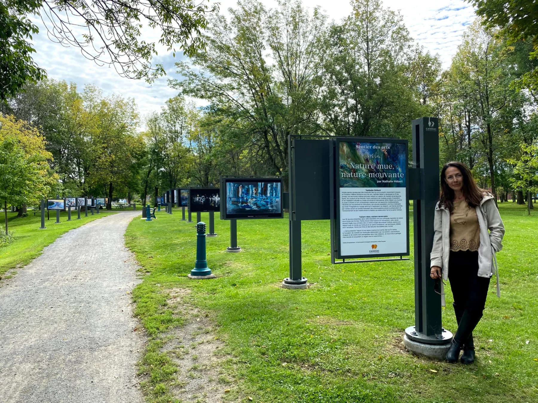 Nathalie Hébert au Sentier des arts, devant le panneau de son exposition.